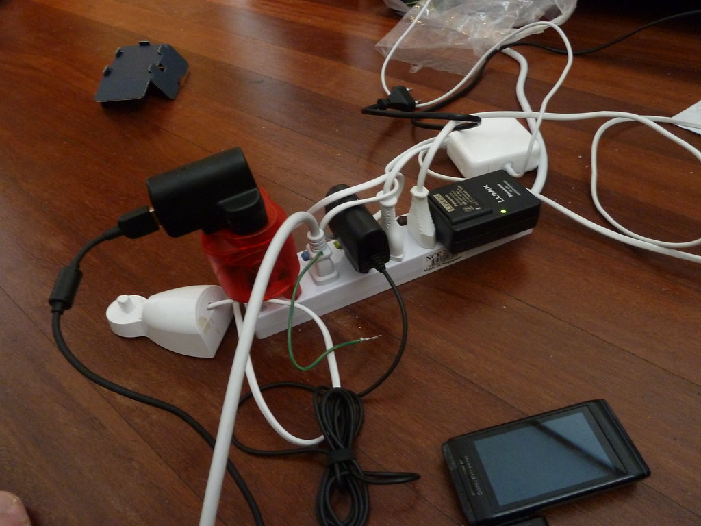 Fotografia licenciada de uma régua de energia e cabos sobre uma superfície.