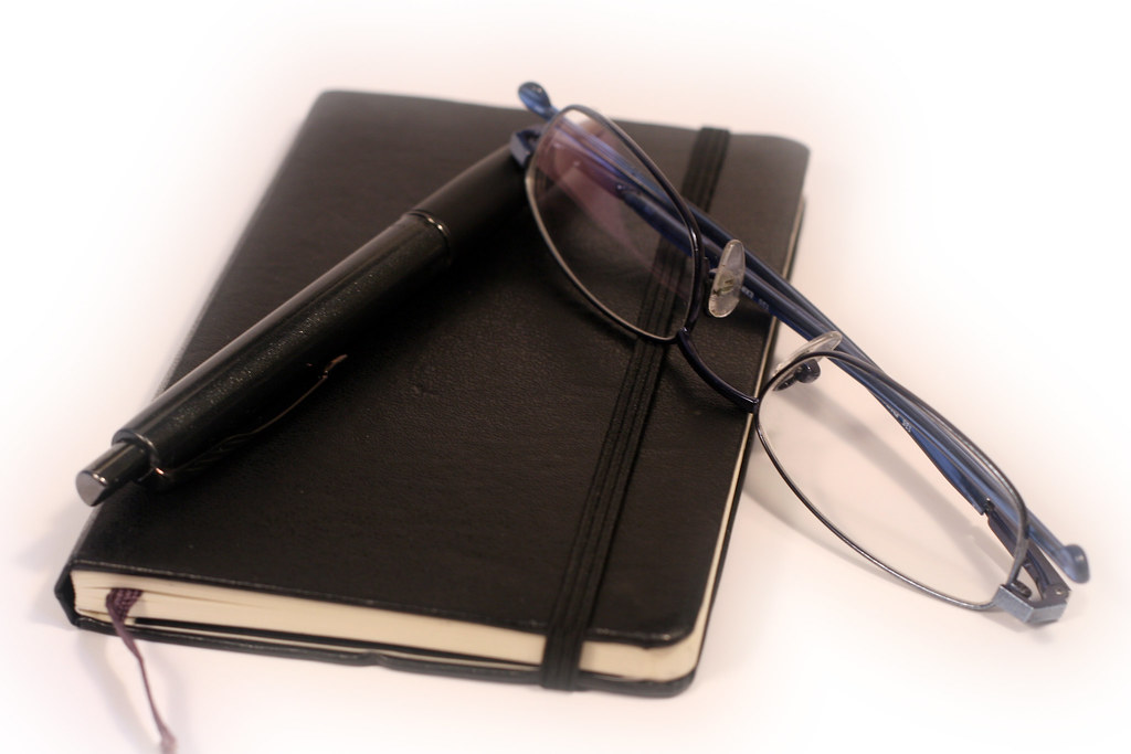 Caderno, caneta e oculos sobre uma mesa